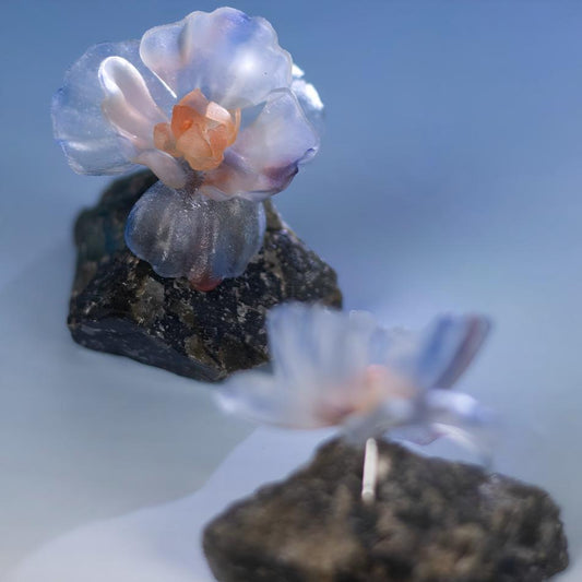 Mist leather flower earrings lifestyle shot on warm peach background with driftwood, showing natural scale and wearable art quality