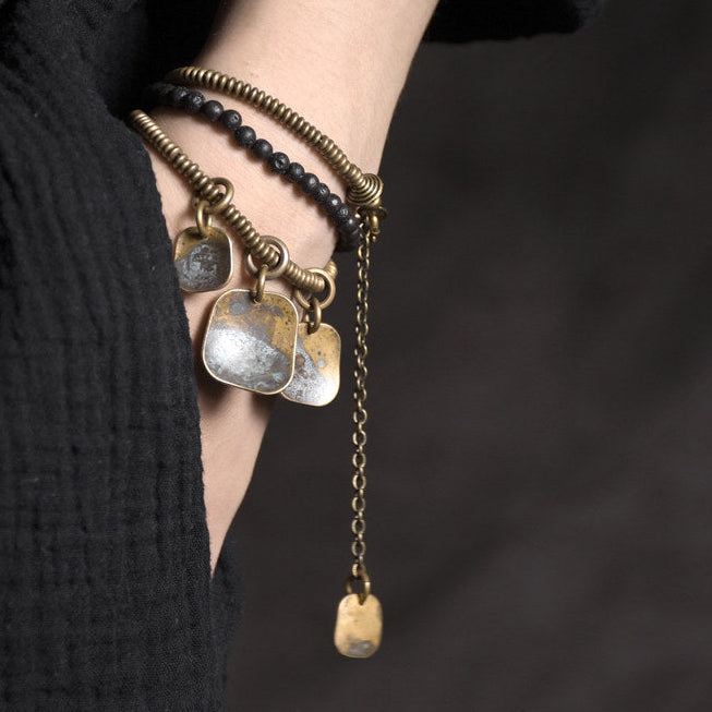 Lava stone and antique brass layered bracelet set flat lay with brand card