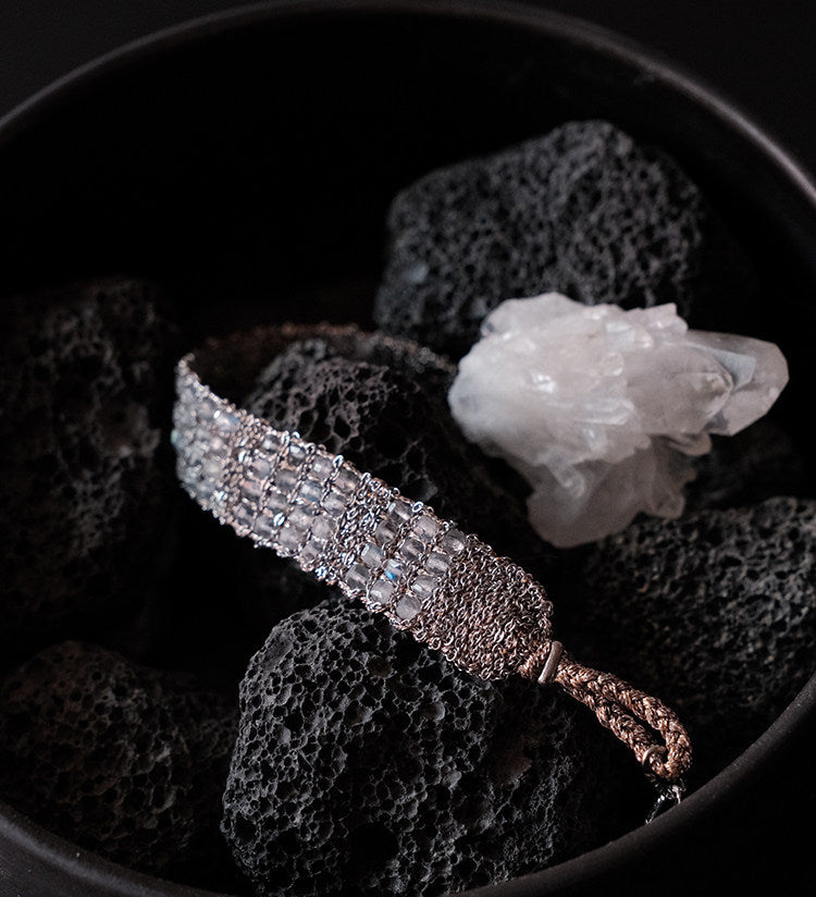 Between the Clouds silver handwoven crystal bracelet in black bowl with white crystal and lava stones