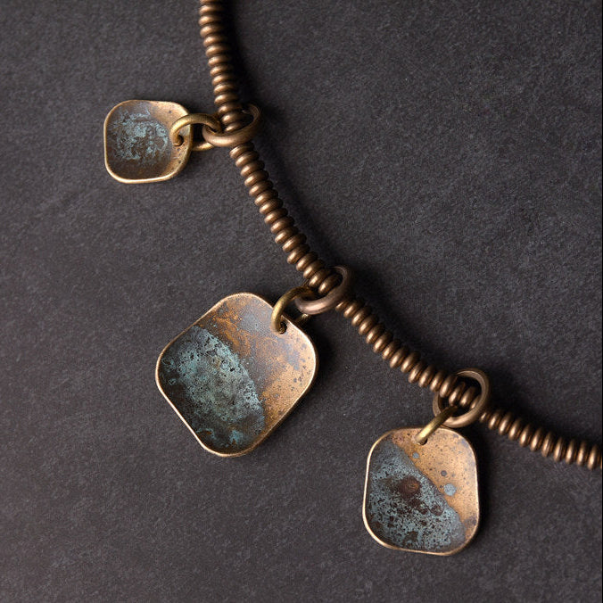 Double-strand lava bead and brass coil bracelet set close-up on slate surface