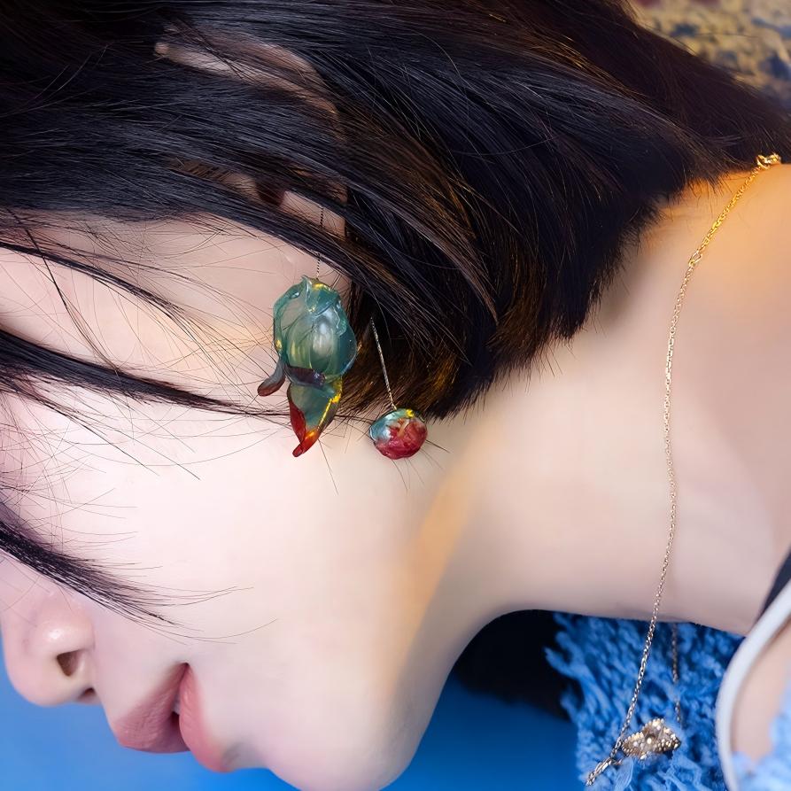 Emo leather drop earrings on dark background, showing silver threader chain and sculptural bead accent with abstract leather form