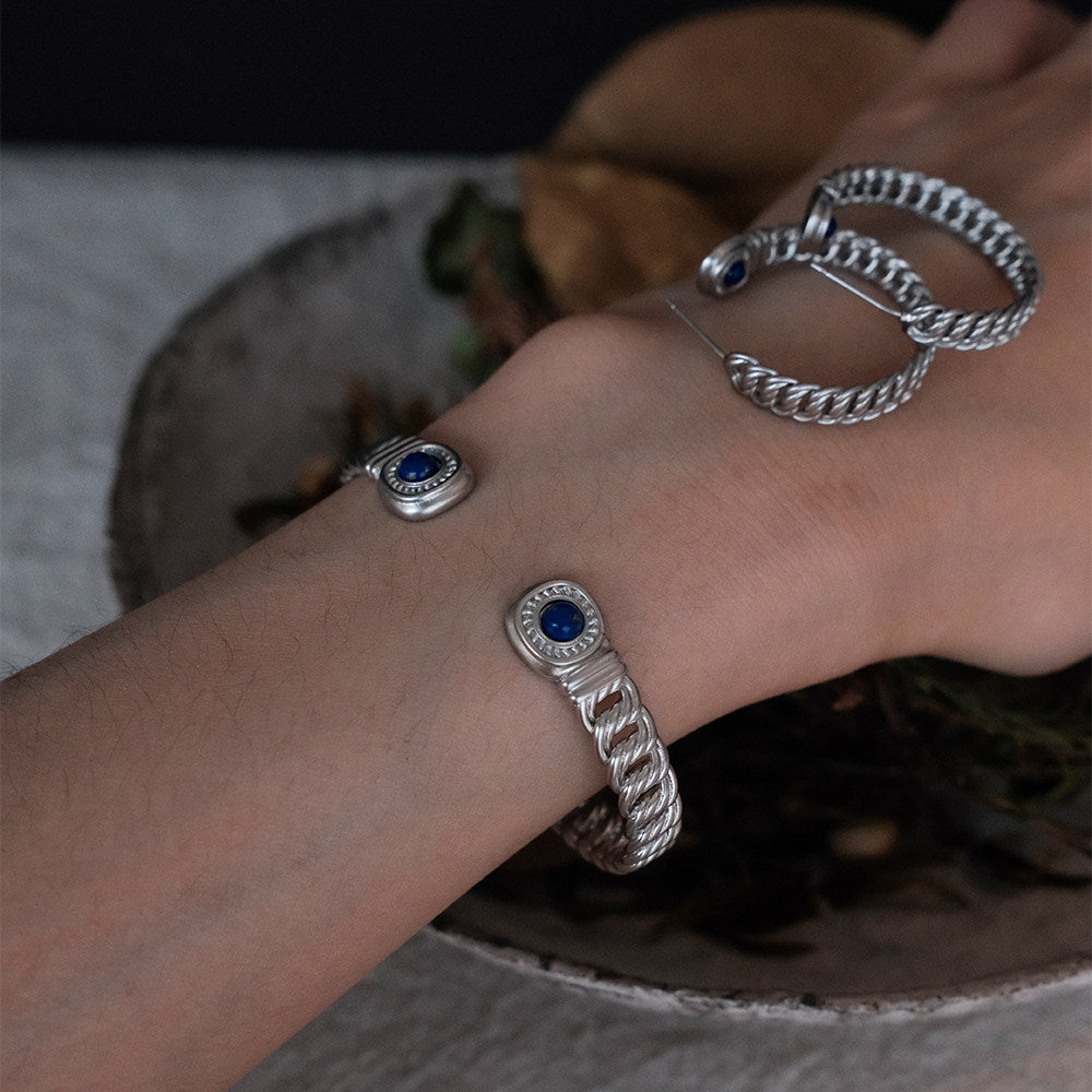 Still and Continuous lapis lazuli palm branch cuff bracelet worn on model wrist, full body view in linen dress
