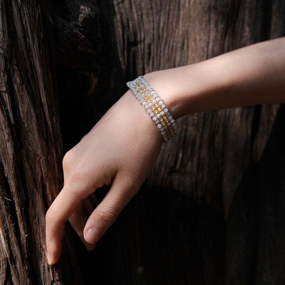 Between the Clouds gold and silver handwoven bracelets side by side on marble surface
